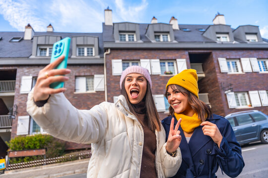 Happy friends taking selfie in urban winter street