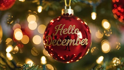 Festive red ornament with hello december text close up with bokeh background and holiday lights