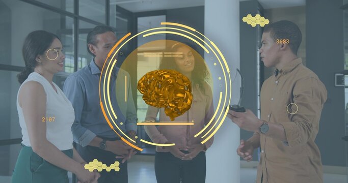 Examining four colleagues in business casual studying gold hologram brain in office, holding remote