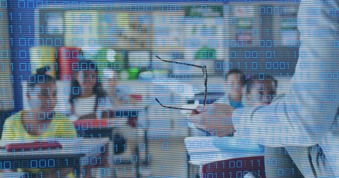 Gesturing mature teacher in lab coat holding eyeglasses and papers in classroom, binary overlaying