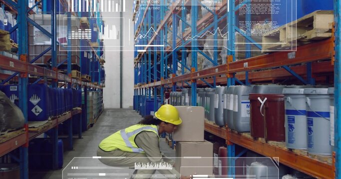 Crouching worker wearing yellow hardhat hi-vis vest handling boxes in blue rack aisle with HUD