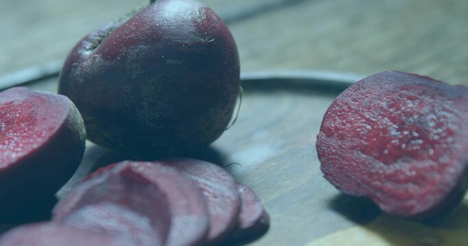 Displaying whole beetroot and sliced rounds resting on wooden cutting board at kitchen countertop