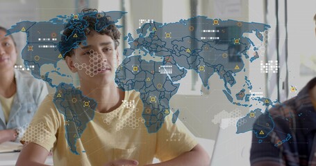 Studying teenage boy wearing yellow T-shirt focusing on laptop at classroom front, hologram overlay