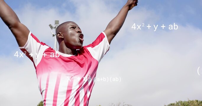 Shouting man wearing red-white striped jersey cheering on field, with light tower and math text