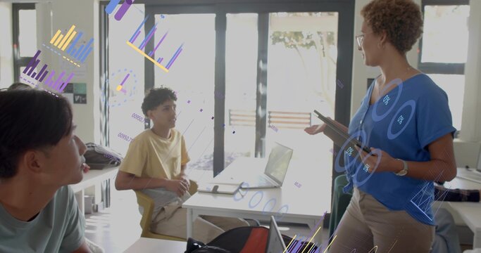 Teaching teacher blue top gesturing toward students in room with laptop notebook tablet, copy space