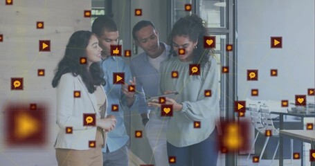 Gathering four business casual professionals viewing tablet in office corridor, with digital icons
