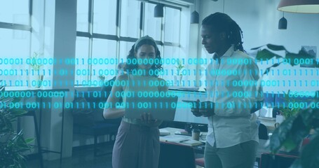 Woman in sleeveless top and man in button-down discussing tablet in office with binary overlay