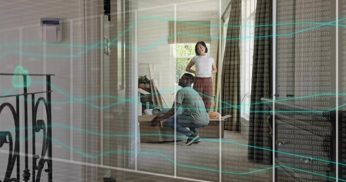 Assembling couple kneeling, watching in living room with wooden table, boxes and binary overlay