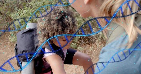 Helping adult steadying purple-top child on trail with pack, rolled pad, DNA overlay with teal dots