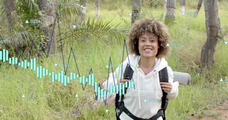 Smiling hiker wearing light hoodie holding backpack with roll mat on grassy trail with charts