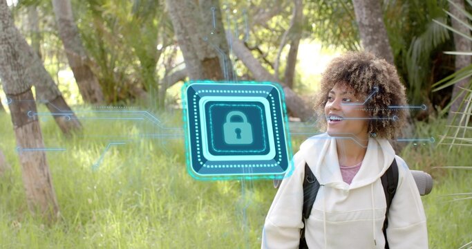 Standing woman wearing hoodie, backpack with rolled mat in sunlit grove, holo padlock, copy space - Powered by Adobe