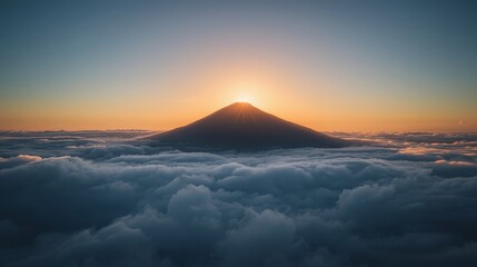 Majestic mountain peak rising above the clouds at sunrise with golden light