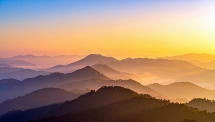 A scenic view of mountain ranges at sunrise, with a hazy atmosphere and golden light illuminating the landscape.