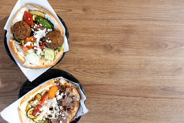 Falafel and meat kebab pita sandwiches on wood