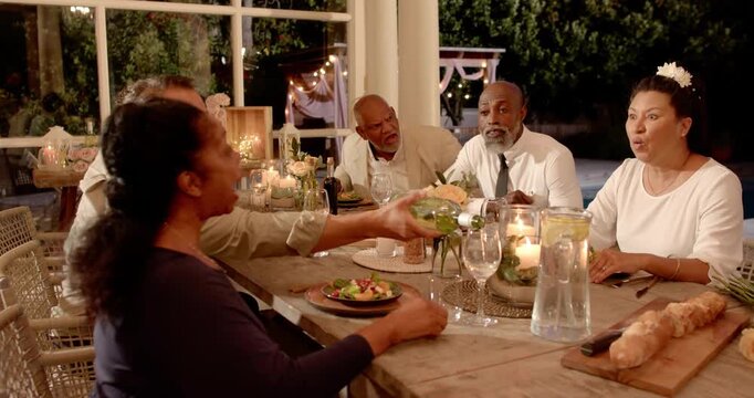 Group passing bowl sparking laser zipping over table diners reacting  and  pouring wine resuming din
