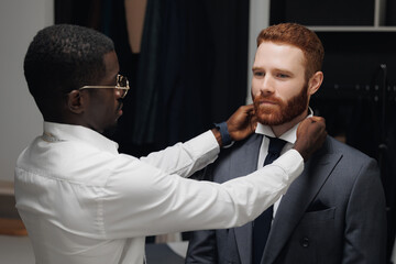 Professional tailor tries on custom men suit on businessman client. Conceptual luxury tailoring shop