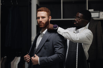 Luxury designer atelier, professional tailor working with client in mens store