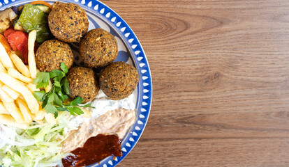 Falafel plate with fries, vegetables and dipping sauces