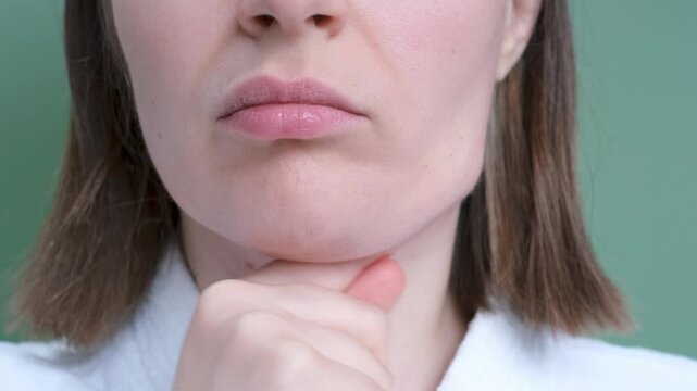 Female face with double chin close-up on green background, front view.