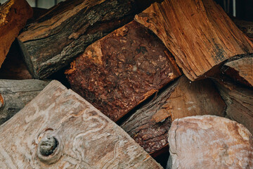 Firewood stacked logs woodpile wooden texture rustic split logs bark fuelwood closeup of dried fireplace wood, earthy brown tones and rough wood grain for cabin heating, winter supply and decor.