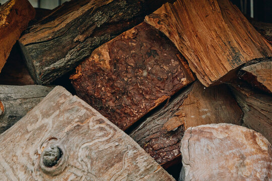 Firewood stacked logs woodpile wooden texture rustic split logs bark fuelwood closeup of dried fireplace wood, earthy brown tones and rough wood grain for cabin heating, winter supply and decor.