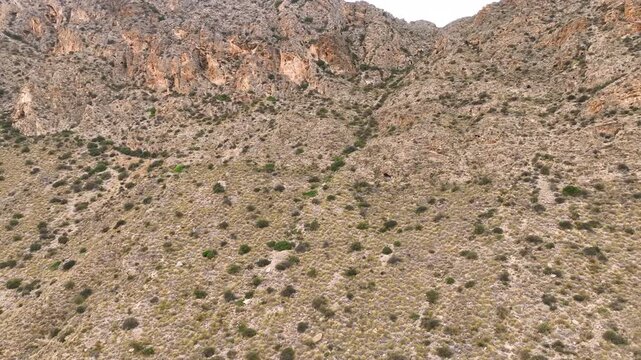 Aerial close up into steep, rocky, and arid Spanish mountainside Pulpi Almeria