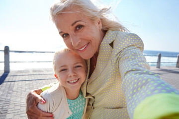 Selfie, grandmother and girl with hug by beach, family bonding and weekend trip for connection. Portrait, care and happy woman embrace child on boardwalk, summer vacation and photography for memory