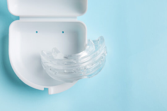 Anti snoring mouth guard made of reusable silicone shown on a white table or blue backdrop. The device is displayed from a side view or top view, clean and minimal, medical product style.