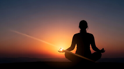 Peaceful silhouette of a woman meditating in a lotus pose against a vibrant sunset sky, symbolizing mindfulness and spiritual wellness