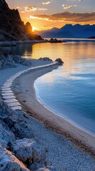 A scenic view of a coastal pathway leading to a lake at sunset. The image features a stone pathway, sandy beach, and mountains in the background, bathed in warm