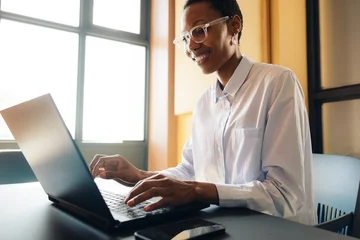 Selbstklebende Fototapeten Sportgeschäft Smiling professional woman working on a laptop indoors  © Jacob Lund