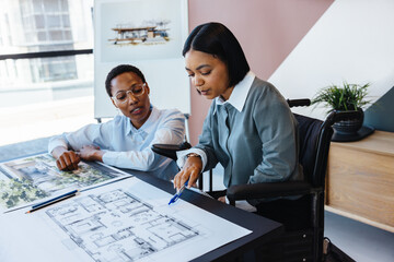 Two women discussing architectural plans in a modern workspace.