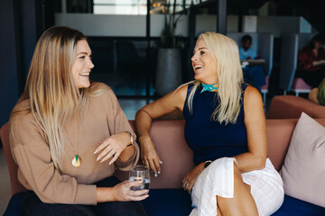 Two women having a friendly conversation in a modern office environment