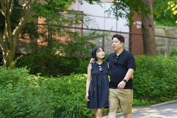 Fototapeta premium A man and woman are walking in a park. The man is wearing a black shirt and the woman is wearing a black dress