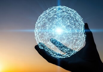 A hand holding a glowing blue digital sphere with a wireframe design against a sunset sky background