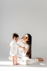 a mother holds her baby's hands as she teaches him to walk, the first steps, space and room for text, mother and child, maternal love