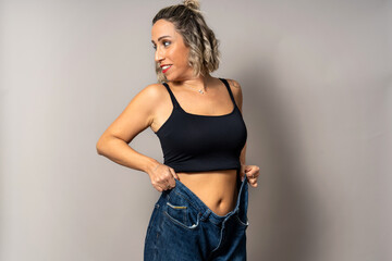 Woman showing significant weight loss results wearing oversized jeans