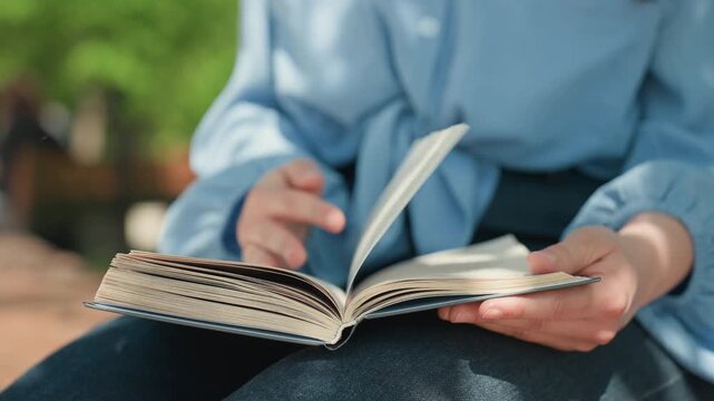 calm caucasian woman enjoying novel on lap, leisurely page turns in sunlit park setting, knotted blouse and denim skirt, close-up on hands and paper, warm relaxed atmosphere with leafy bokeh