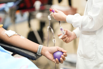 Selective focus hand of blood donor squeezing rubber ball to pump into bag while donating blood in hospital.Donation for emergency surgery.Save life and medical treatment concept.