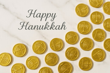Golden chocolate gelt coins with menorah designs arranged on white marble background, festive Hanukkah greeting text above in elegant script, bright and cheerful holiday mood