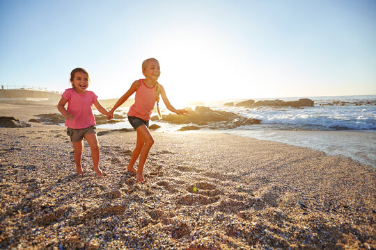 Girl, sisters and running at beach, holding hands and excited with space, smile or bonding on summer holiday. Kids, siblings and happy by ocean, playful or love for fun games by sea on vacation