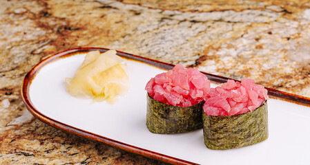 Fresh sushi rolls served with pickled ginger on granite table