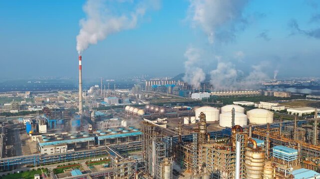Aerial shot of large industrial chemical plant  and oil refinery with smoke stacks emitting smoke, causing air pollution.