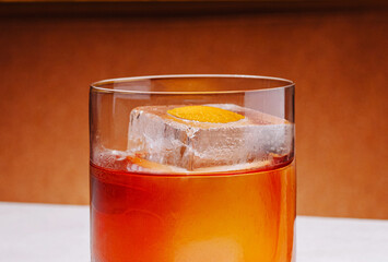 Craft cocktail served in a clear glass with ice and orange garnish at a bar