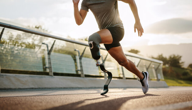 A person with a prosthetic leg runs on a track during the day, demonstrating athleticism.