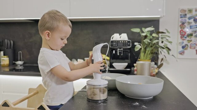 Toddler boy cooking with blender in kitchen
