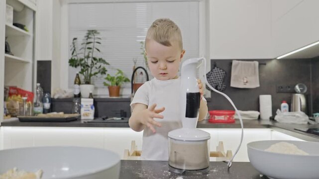 Curious toddler learning to use immersion blender