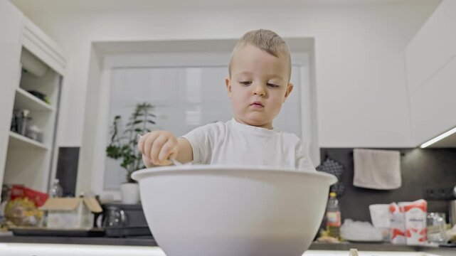 Toddler boy learning to cook in the kitchen