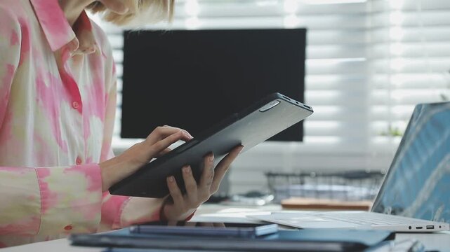 Two financial accountants analysing business spreadsheets on laptop computer, sitting at office desk, looking through paper documents, using calculator working with databases, checking excel tables