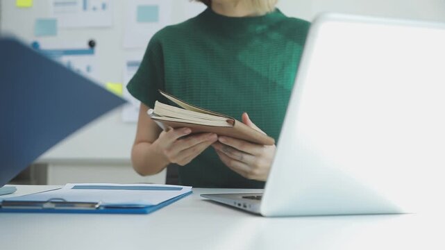 Two financial accountants analysing business spreadsheets on laptop computer, sitting at office desk, looking through paper documents, using calculator working with databases, checking excel tables